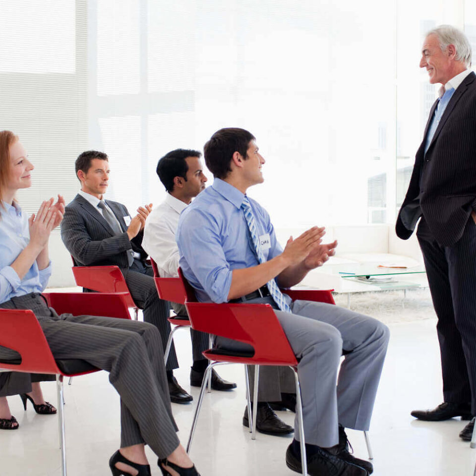 A diverse group of professionals applauding enthusiastically at a business conference.