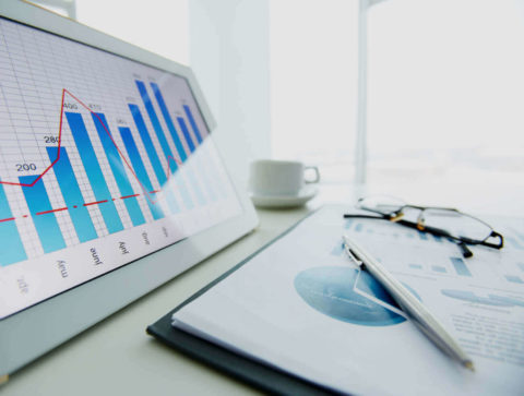 Business documents and tablet displaying a graph on a desk.