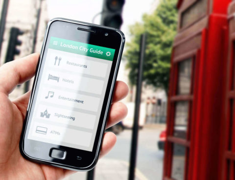 Hand holding smartphone with city guide on screen in London