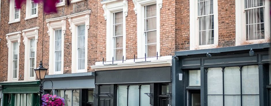 Historic brick buildings with white-trimmed windows and black shopfronts on a city street
