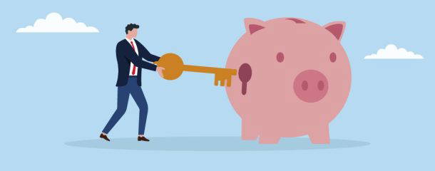 Businessman inserting key into piggy bank symbolising savings and investment planning