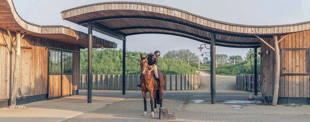 Modern equestrian stable with rider mounted on horse